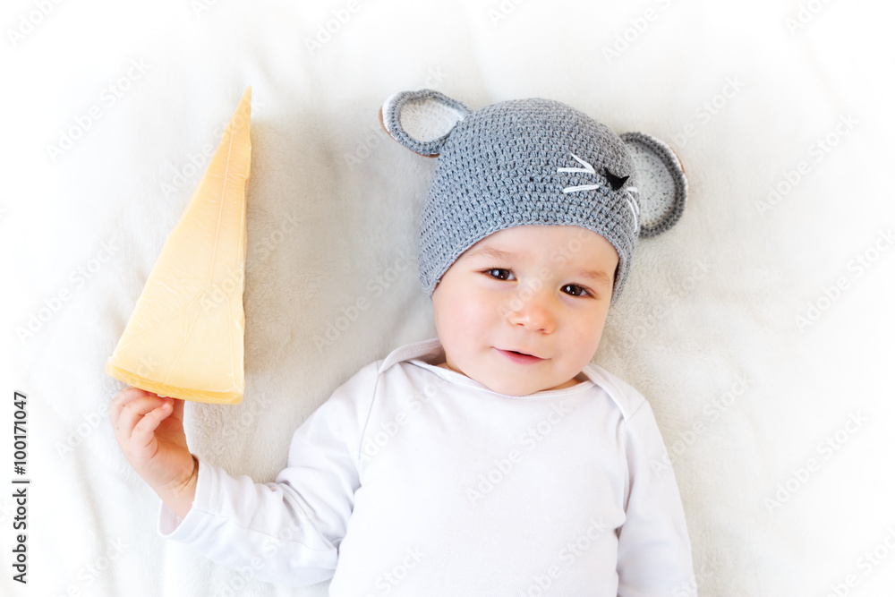 Baby boy in mouse hat lying on blanket with cheese