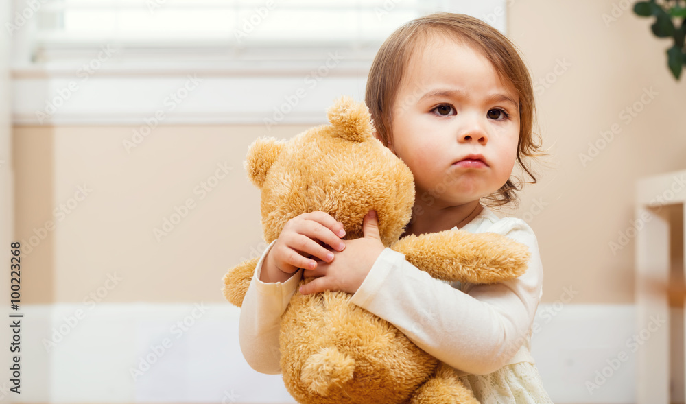 Toddler girl tightly holding her teddy bear