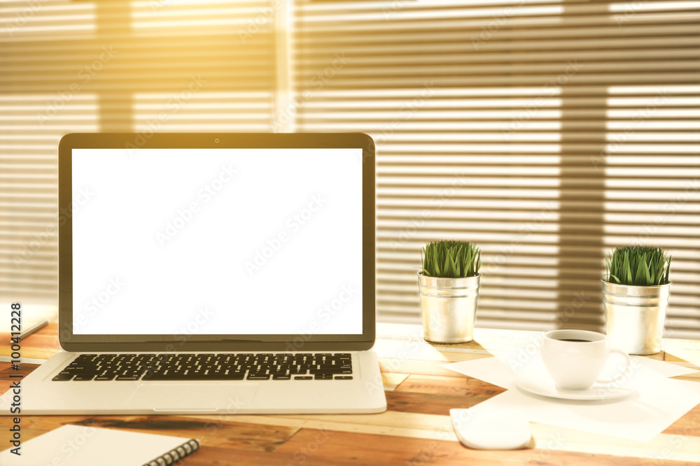 Blank laptop screen on wooden table with cup of coffee and grass