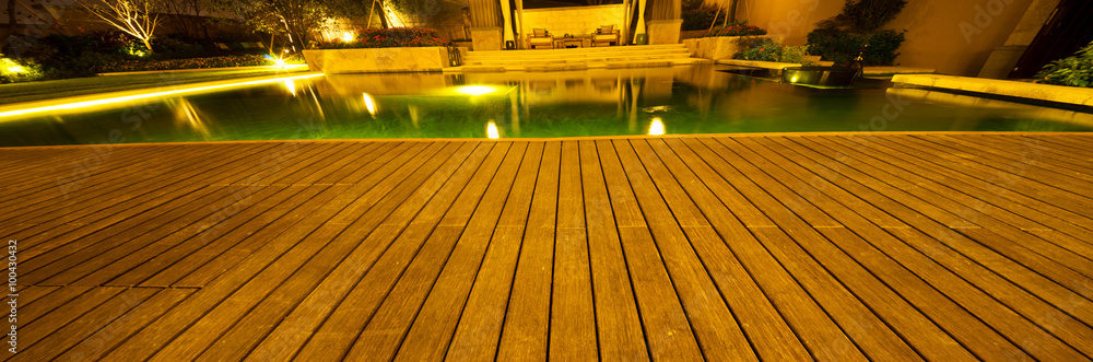 empty wooden floor outside building near pond at night