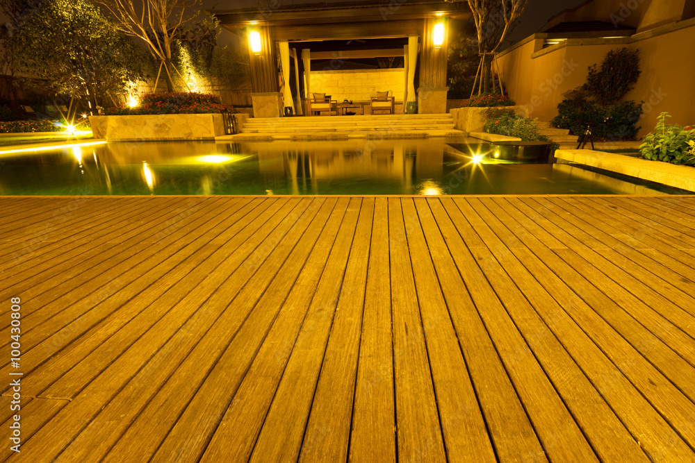 empty wooden floor outside building near pond at night