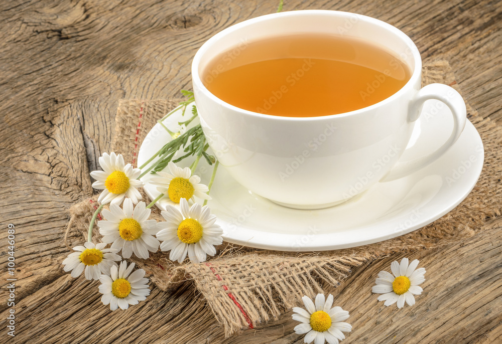 Cup of tea and chamomiles on wooden background