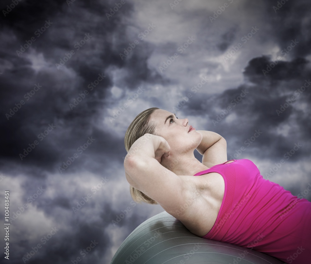 Composite image of muscular woman exercising on ball