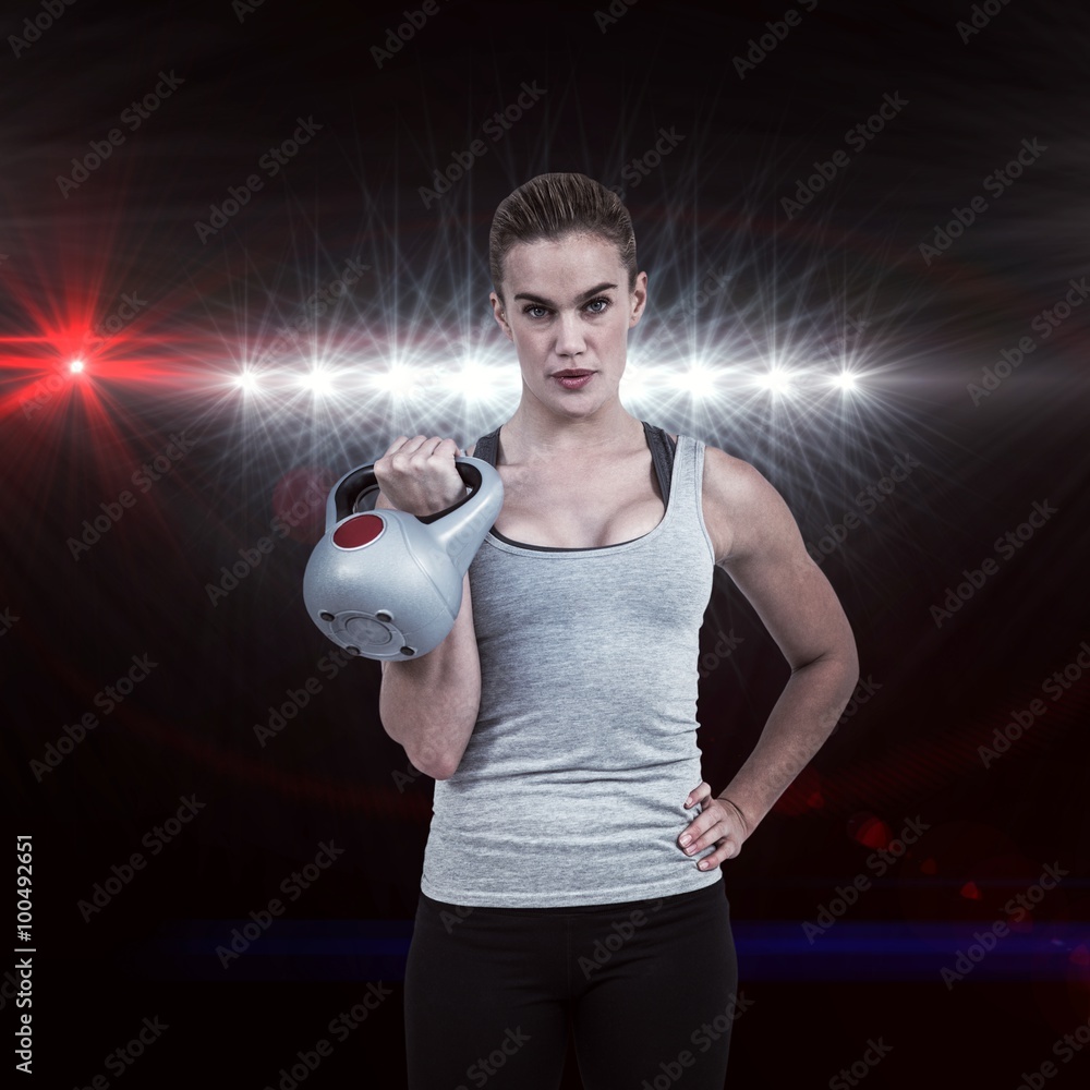 Composite image of serious muscular woman lifting kettlebell 