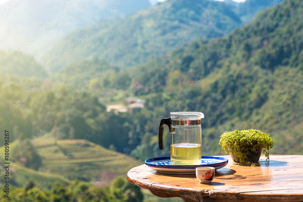 Hot green tea and tea plantation field view in background.