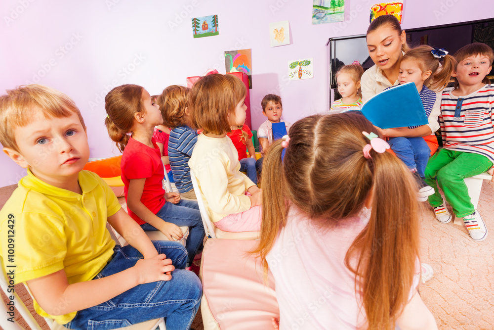 Teacher read book to little boys and girls 