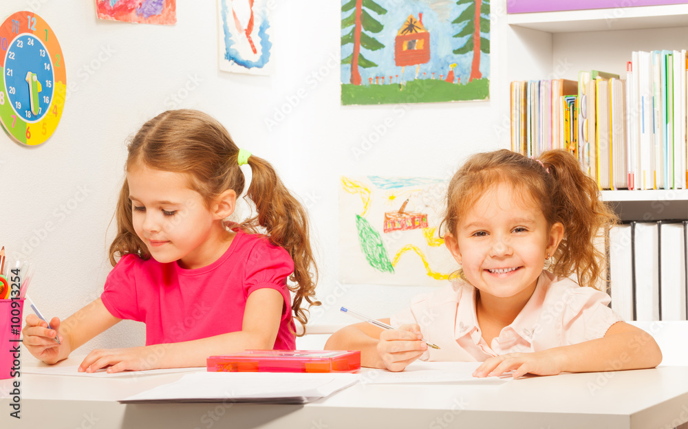 Two clever schoolgirls writing at the copybook