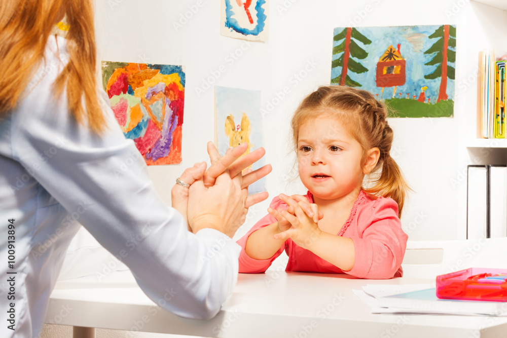 Little preschooler with her teacher at the table