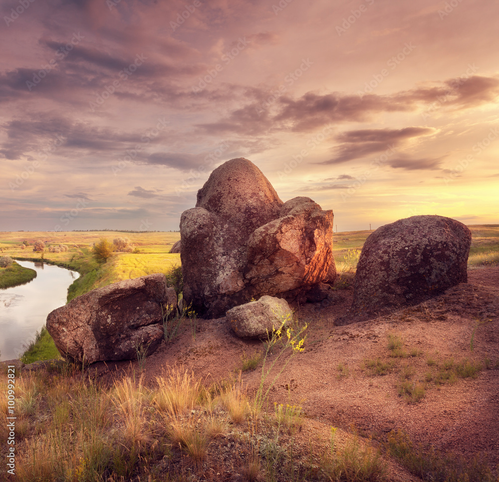 Beautiful summer sunset at the river with old stones