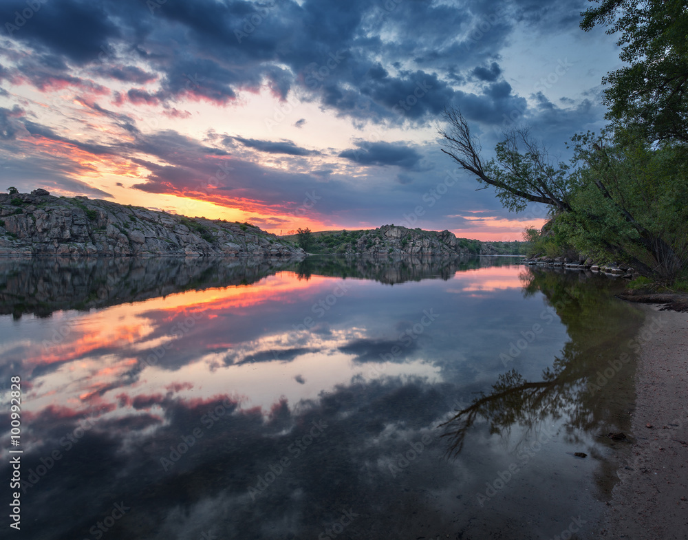 Beautiful sunset at the beach. Clouds reflected in water.