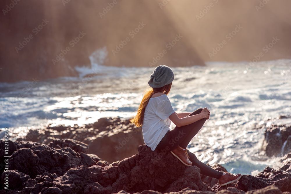 Woman enjoying sunset on the rocky coast