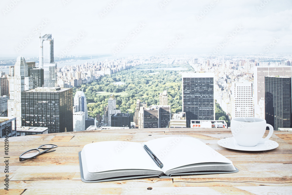 Open notebook and cup of coffee on the wooden table