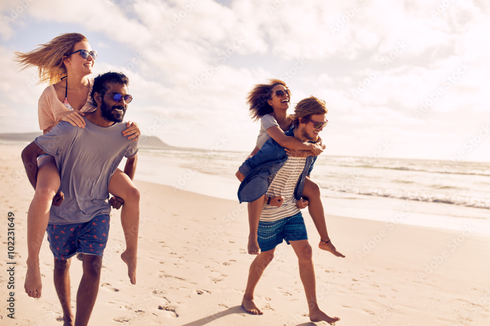 Couples piggybacking on sea shore