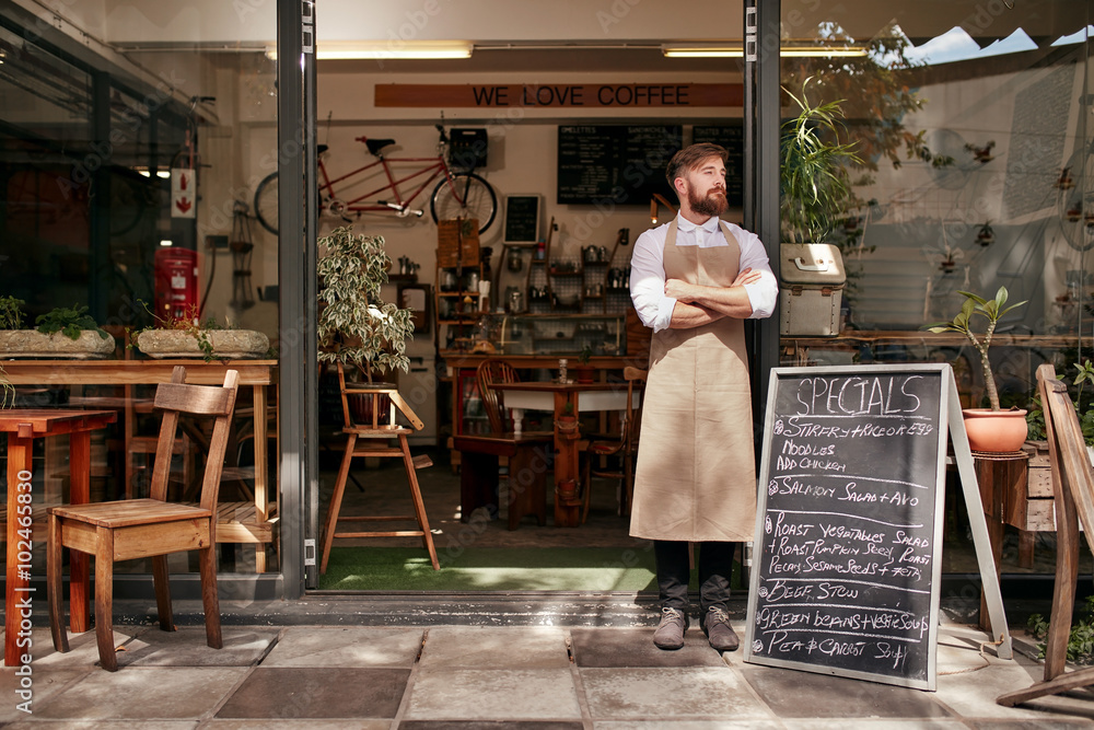 Young man standing at entrance of his coffee shop