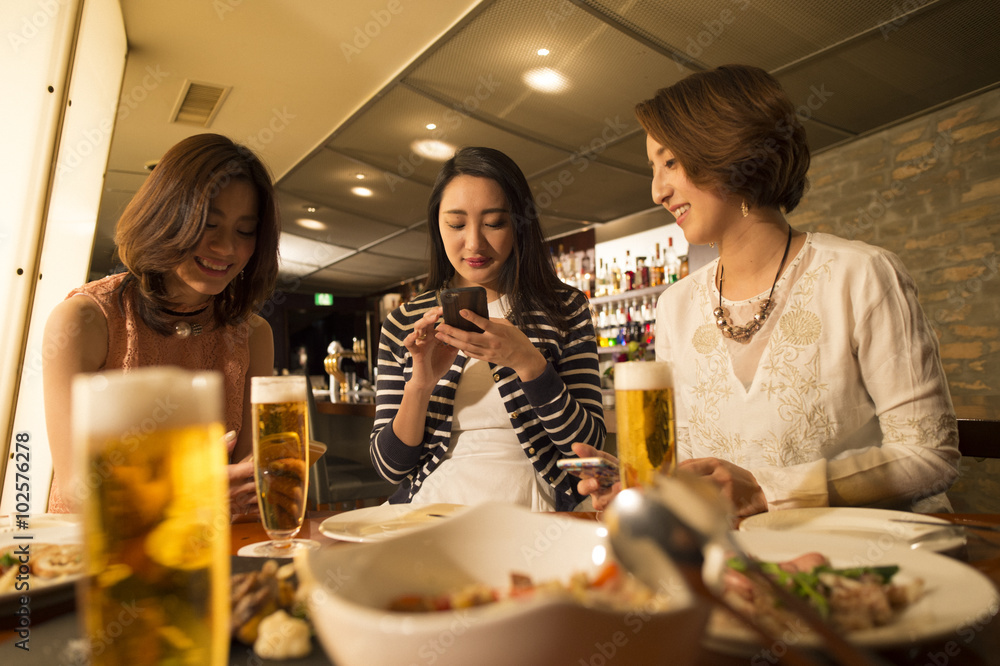 三名女性在餐厅喝啤酒前看到了一部手机