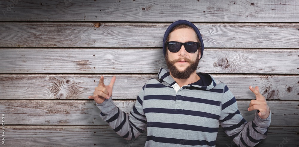 Composite image of hipster showing rock and roll hand sign