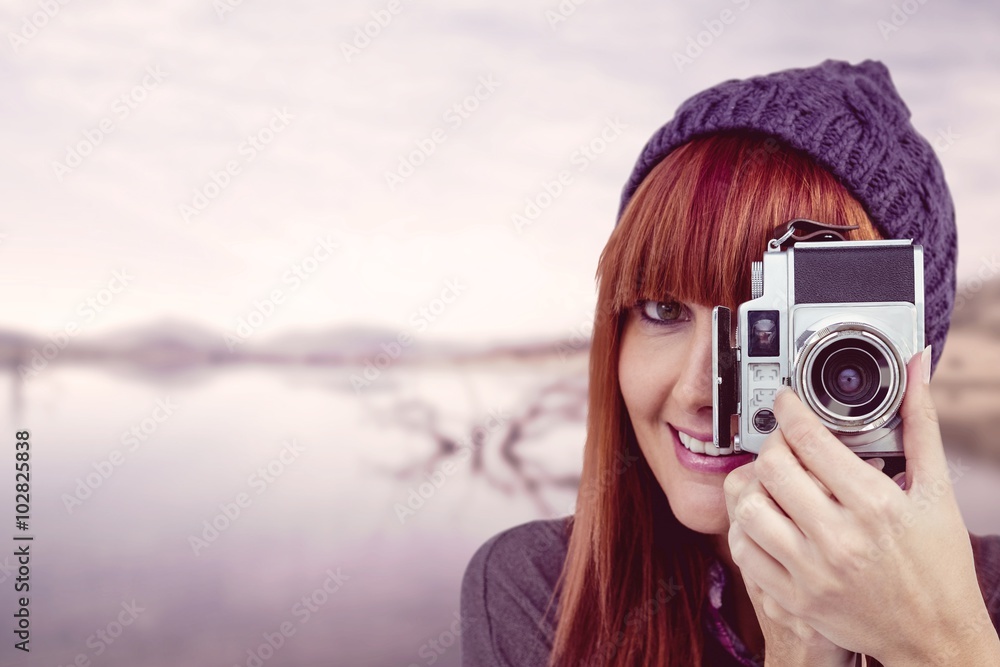 Smiling hipster woman taking pictures with a retro camera