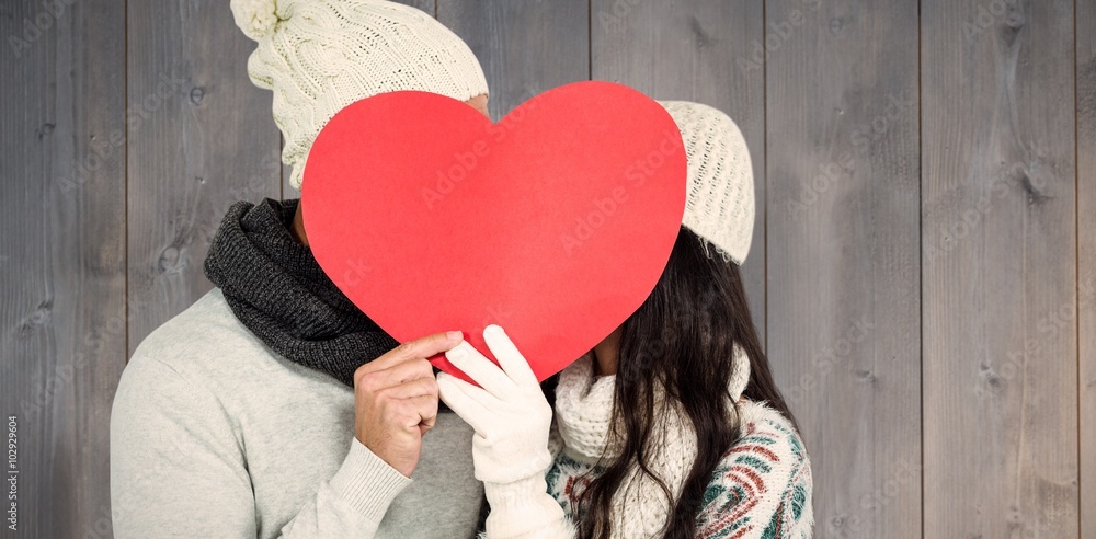 Composite image of smiling couple holding paper heart