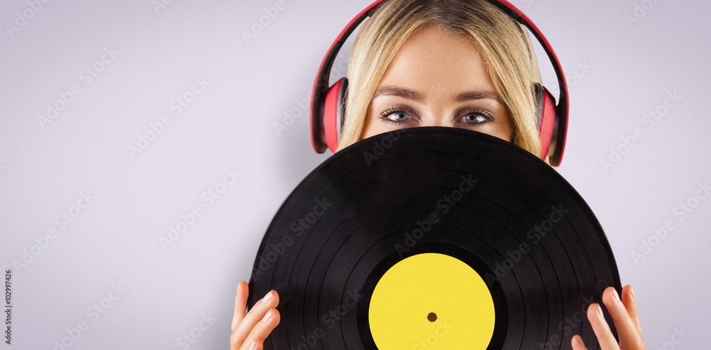 Composite image of portrait of a beautiful woman holding a vinyl