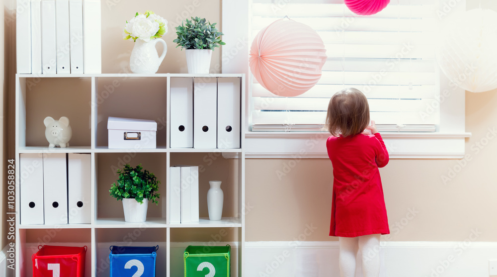 Toddler girl peeking out the window