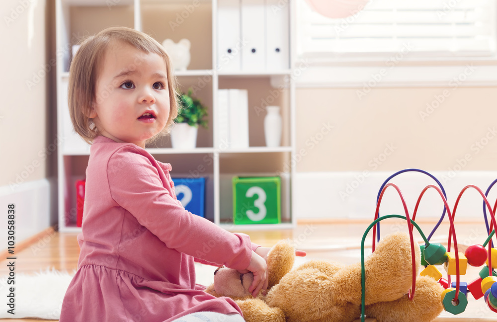 Happy toddler girl playing with her teddy bear