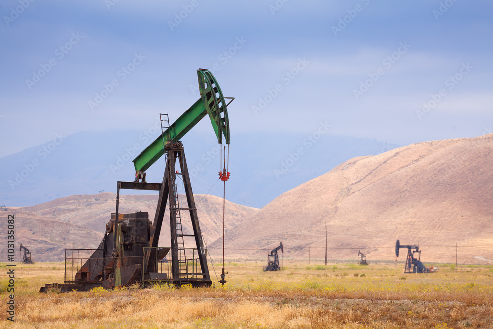 Oil pumps at large oilfield in huge mountains