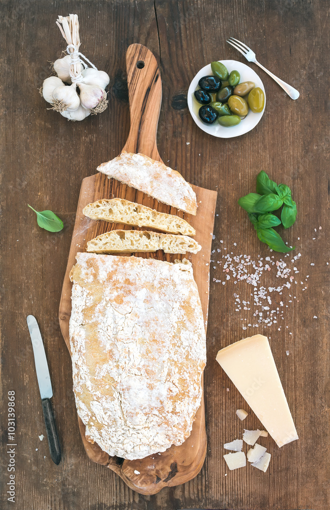 Freshly baked ciabatta bread with garlic, mediterranean olives, basil and Parmesan cheese on serving