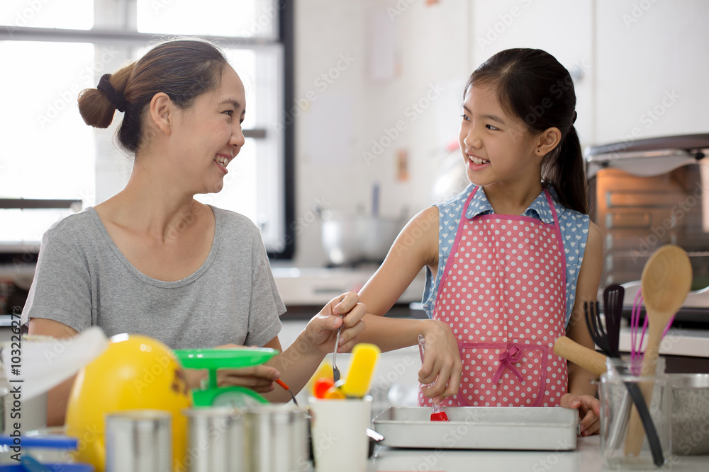 Little Asian cute chef cooking a bakery in kitchen with mother