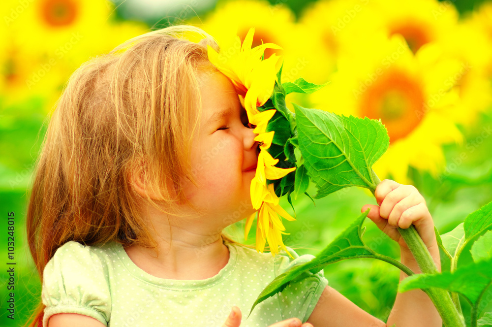 little girl smelling a sunflower