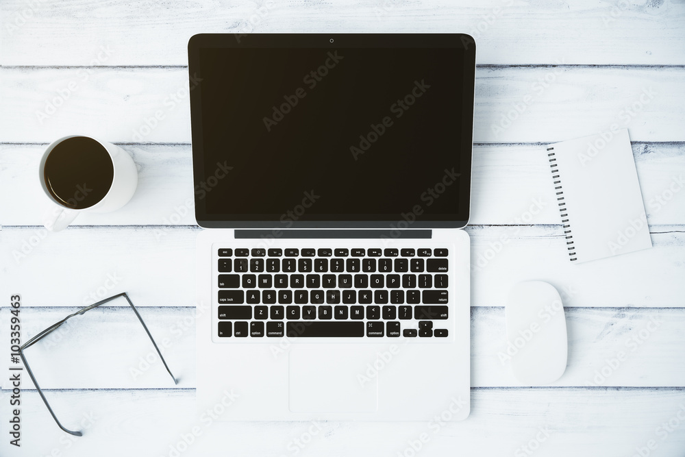 Blank black laptop screen with cup of coffee, eyeglasses and dia