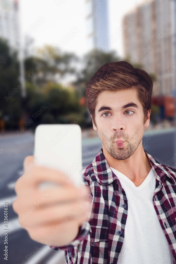 Composite image of man making face while taking selfie