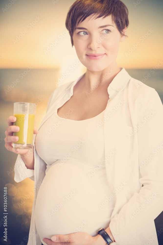 Composite image of pregnant woman holding glass of orange juice