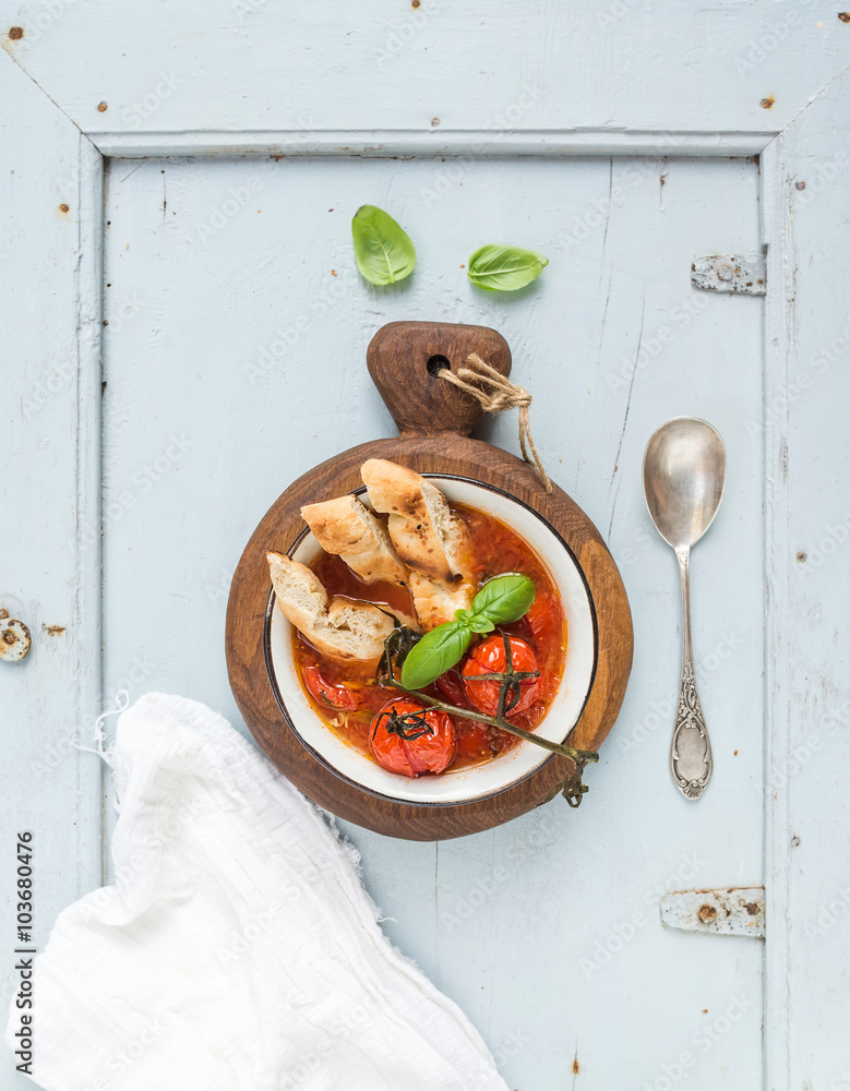 Italian tomato, garlic and basil soup Pappa al Pomodoro in metal bowl with bread on rustic wooden bo