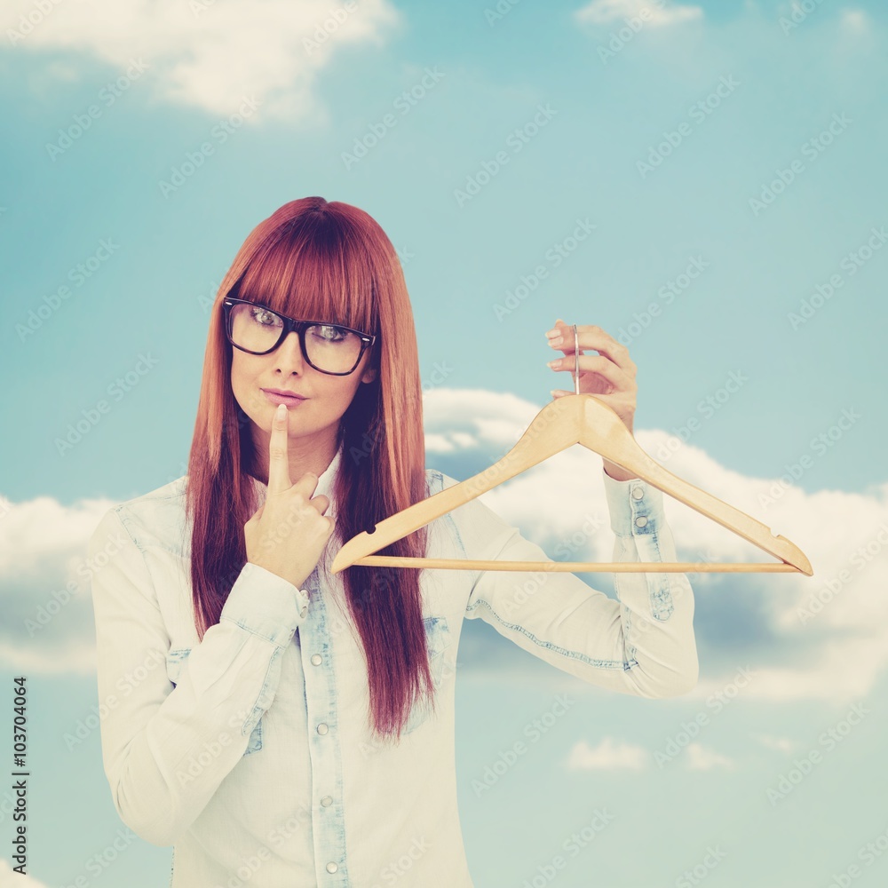 Composite image of smiling hipster woman holding a clothes hanger