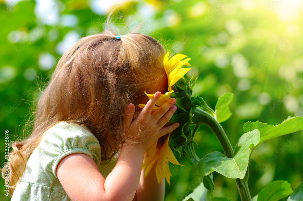 little girl smelling a sunflower