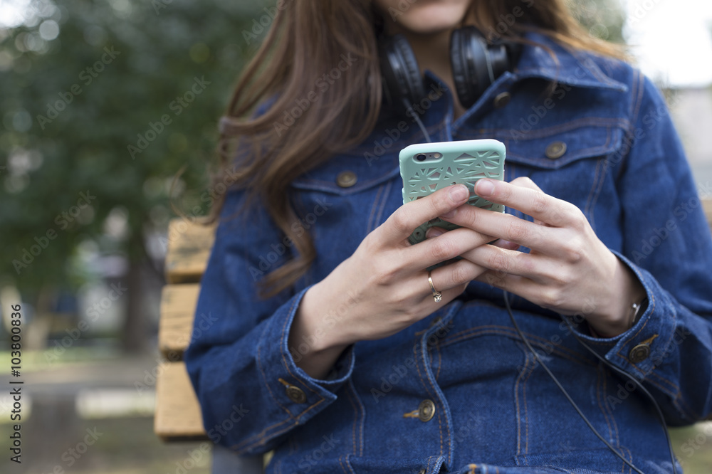 Young women are looking at the smartphone sitting on a bench in the park