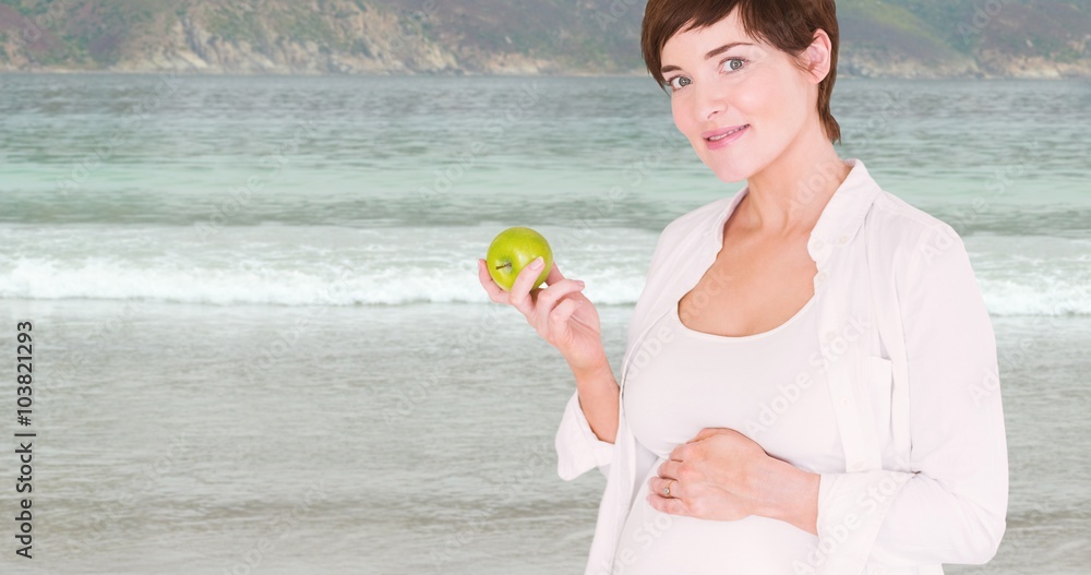 Composite image of portrait of pregnant woman holding green apple