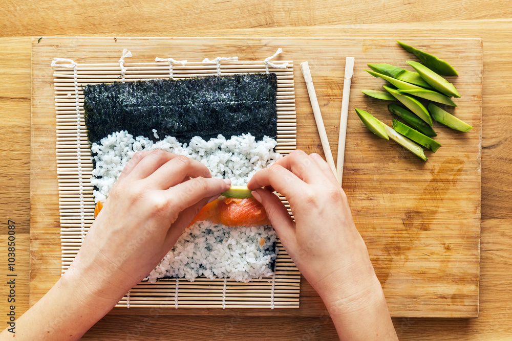 Preparing sushi. Salmon, avocado, rice and chopsticks on wooden table.