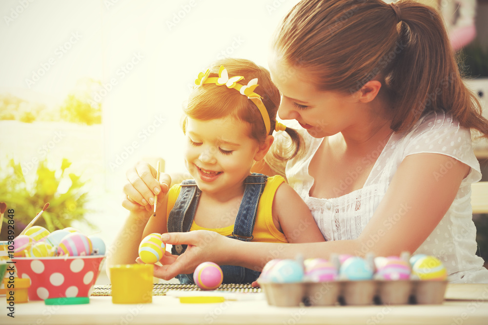 happy family mother and child girl paints eggs for Easter