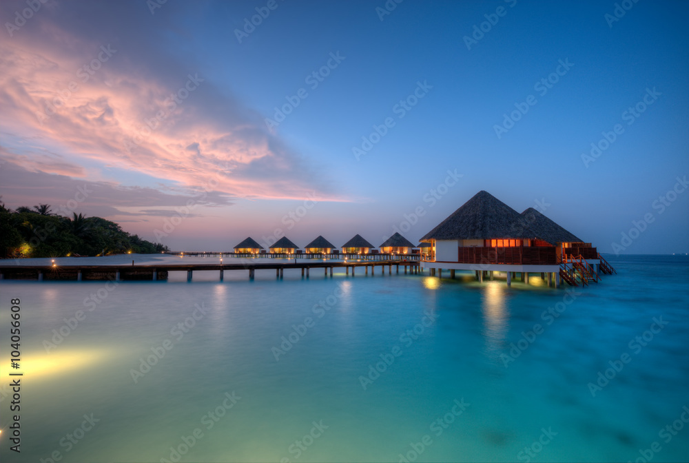 Water villas on Maldives resort island in sunset