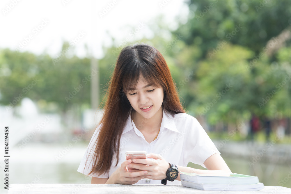 Asian student with uniform using smartphone in university