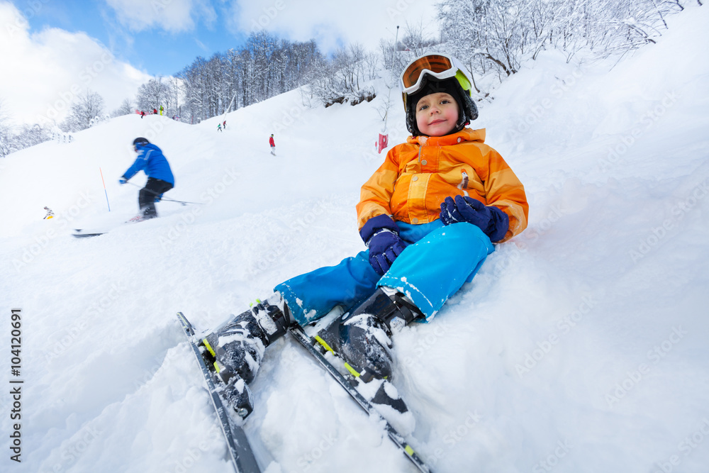 儿童坐在滑雪道边的雪地里休息