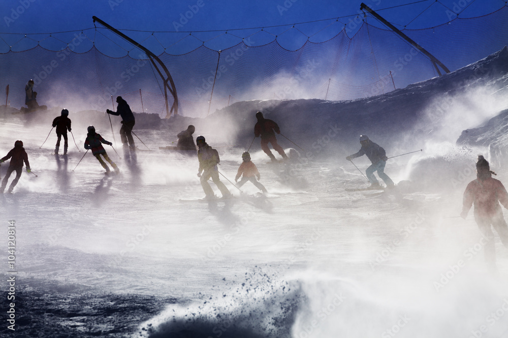 Many skiers silhouettes over sunset light