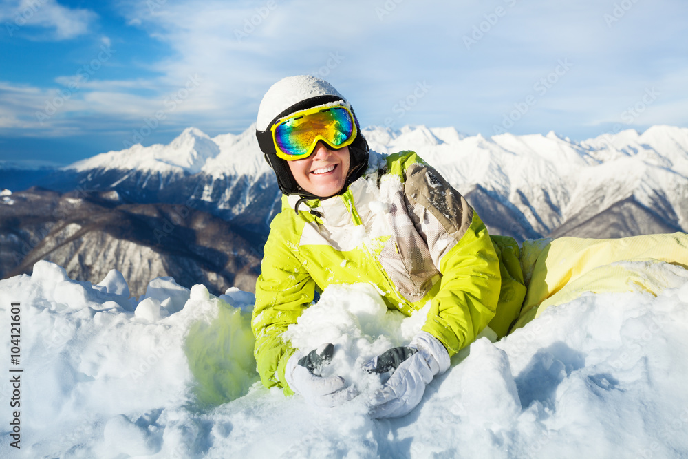 快乐的滑雪者女人躺在雪地里休息，面带微笑