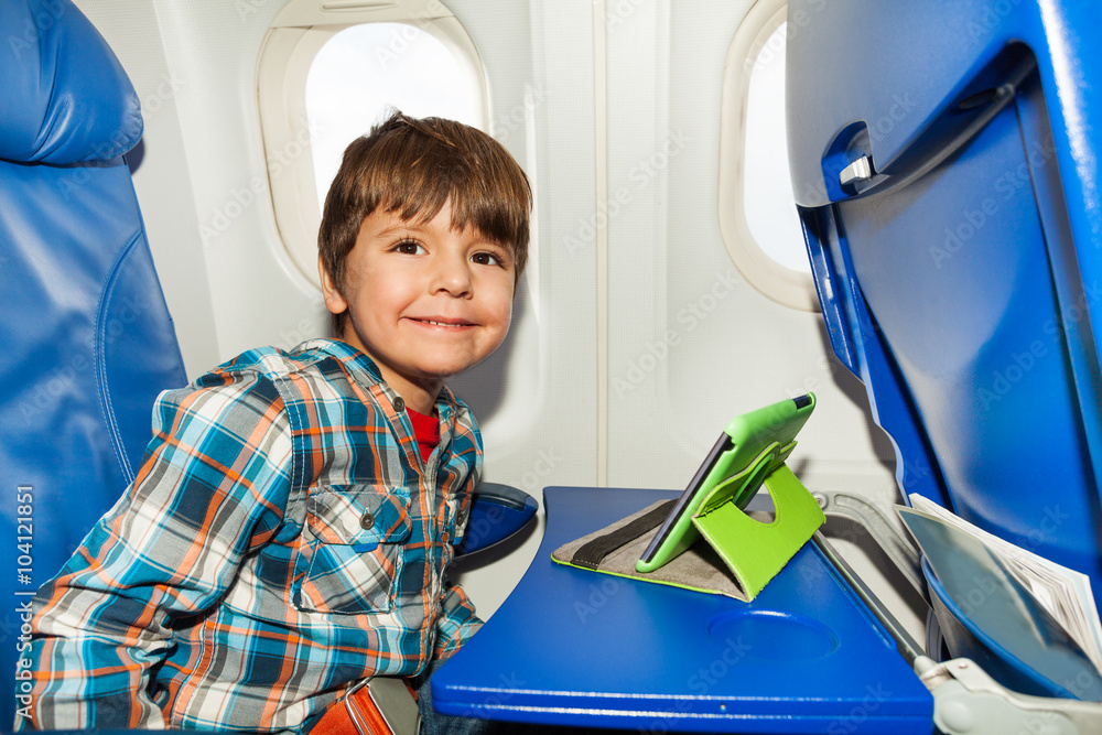 Little boy in airplane chair play tablet pc