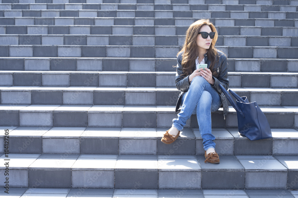 Young woman with sunglasses is sitting on the stairs