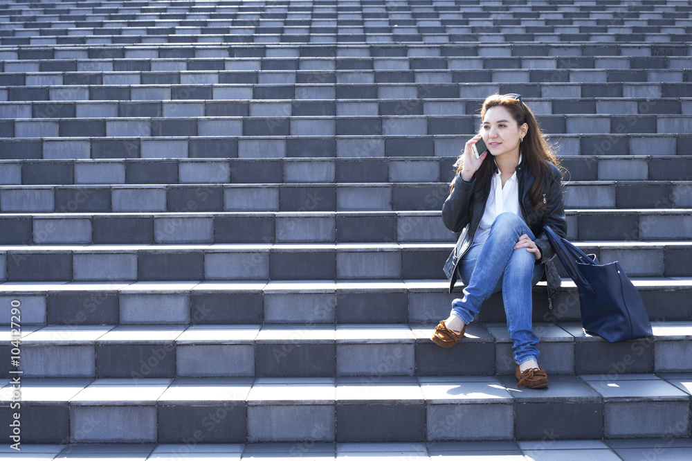 戴着墨镜的年轻女子坐在楼梯上打电话