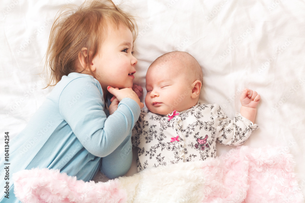 Toddler girl playing with her newborn sister