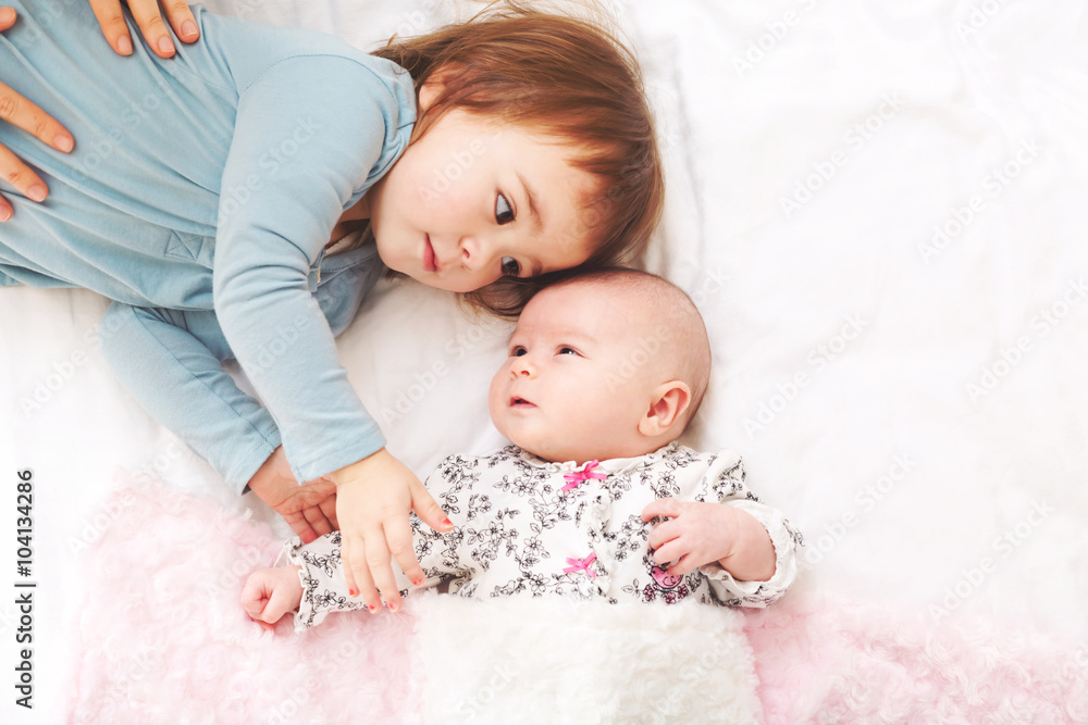 Toddler girl playing with her newborn sister