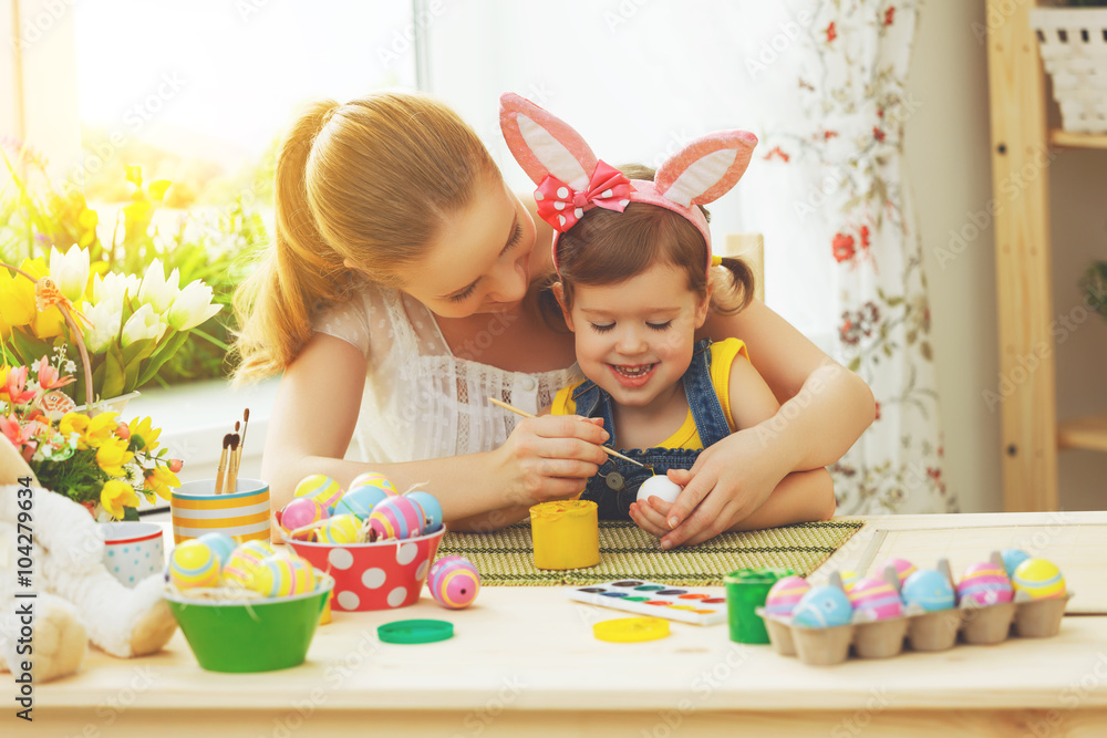 happy family mother and child girl paints eggs for Easter